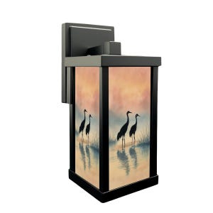 May include: Black outdoor wall lantern with a rectangular design. The lantern features a scenic image of cranes in a marsh at sunset. The background has shades of orange, pink, and blue. The lantern is mounted on a black bracket.