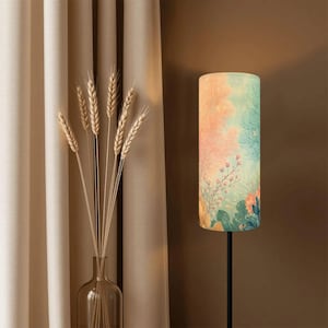 May include: A floor lamp with a cylindrical lampshade featuring a watercolor design of coral and aquatic plants in shades of pink, blue, and green. The lamp has a black metal stand and is placed next to a vase of wheat stalks.