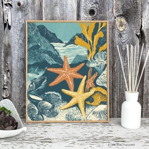 May include: A framed print featuring a sea-themed illustration. The artwork depicts starfish in shades of orange and yellow, set against a backdrop of teal water, rocks, and seaweed. The print is in a wooden frame, evoking a coastal aesthetic.