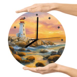 May include: Round wall clock featuring a coastal scene with a lighthouse, rocks, and ocean waves under a sunset sky. The clock has black hands and square hour markers. The clock is held by two hands.