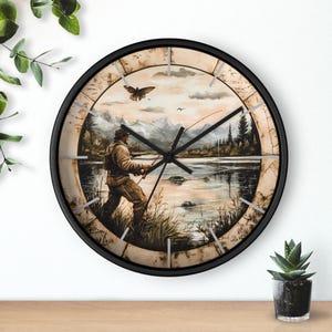 May include: A black framed wall clock with a vintage-style image of a person fishing in a lake. The image is surrounded by a decorative border with Roman numeral markings.