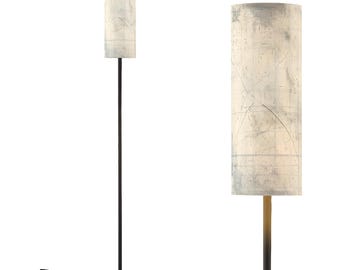 May include: A tall, modern floor lamp with a cylindrical lampshade. The lampshade has a cream-colored background with a map-like design in shades of gray and blue. The lamp has a black metal pole and a round base.