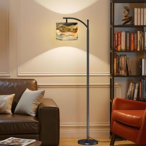 May include: A black arc floor lamp with a rectangular lampshade featuring a landscape design in shades of brown, beige, and blue. The lamp is positioned next to a brown leather sofa and a bookshelf.