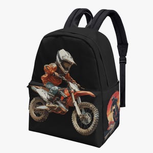 May include: A black backpack featuring a graphic print of a rider in an orange jacket and white helmet on a dirt bike. The design includes a smaller circular sunset scene with a silhouette of a rider on the side pocket, along with adjustable straps.