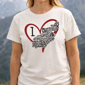 Op de afbeelding: Crèmekleurig T-shirt met een rode hartomtrek. Binnenin het hart bevindt zich een staatsvormig ontwerp gevuld met staatsnamen. Het T-shirt heeft een ronde hals en korte mouwen.