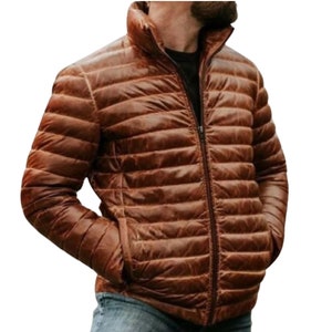 Könnte beinhalten: Eine braune Steppjacke mit Reißverschluss. Die Jacke hat einen Stehkragen und eine leicht strukturierte Oberfläche.