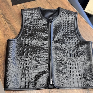 May include: A black leather waistcoat with a zip fastening and a crocodile-embossed pattern.