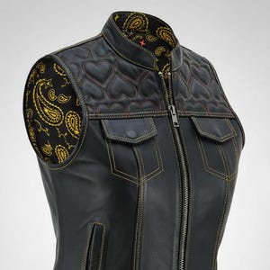 Könnte beinhalten: Schwarze Lederweste mit gestepptem Herzmuster auf den Schultern und Paisley-Futter. Sie hat einen Reißverschluss vorne, zwei Brusttaschen und zwei Eingrifftaschen. Die Weste hat gelbe Nähte und den Text "LeatherBarrowNY" unten.