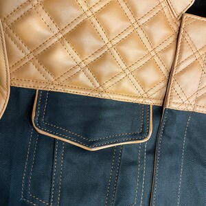 Puede incluir: Primer plano de una chaqueta con una secci&oacute;n superior de cuero acolchado de color canela y un cuerpo de tela verde oscuro. La chaqueta tiene un bolsillo con ribete y costuras de color canela.