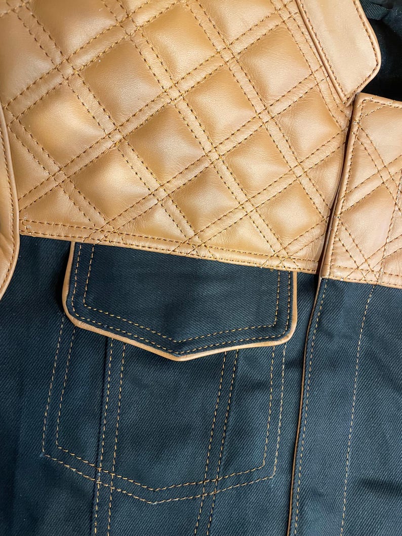 Puede incluir: Primer plano de una chaqueta con una secci&oacute;n superior de cuero acolchado de color canela y un cuerpo de tela verde oscuro. La chaqueta tiene un bolsillo con ribete y costuras de color canela.
