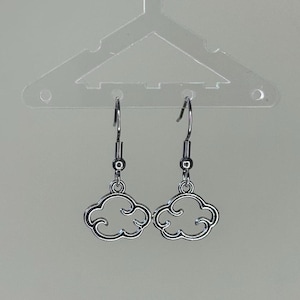 May include: A pair of silver dangle earrings with a cloud design. The earrings are hanging from a clear plastic hanger.