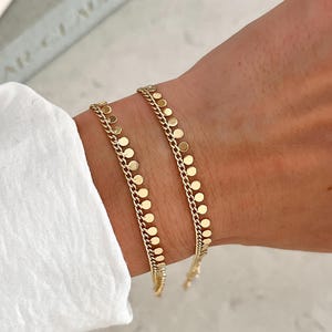 Bracciale con dischi shaker placcati in oro 14 carati e delicata catena a frange con monete.