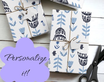 May include: Three white gift boxes with blue and black floral designs and the name "Cecilia Marie" printed on them. The boxes are tied with twine and have a white tag attached to each. The boxes are on a white wooden surface.