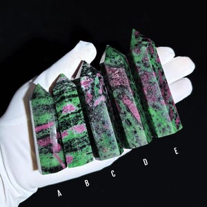 May include: Five green and pink gemstone points, labelled A to E, are arranged in a row on a white surface. The points are all different sizes and shapes, but they all have a similar green and pink colour pattern.