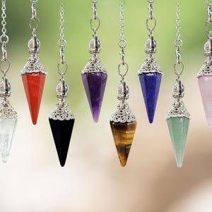 May include: Seven different coloured crystal pendulums with silver chains and ornate silver tops. The crystals are amethyst, rose quartz, tiger's eye, clear quartz, red jasper, black obsidian, and green aventurine.