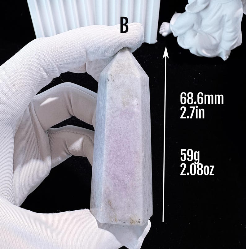 Puede incluir: Un obelisco de cristal morado claro, de 68,6 mm de altura y 59 g de peso. El cristal tiene forma hexagonal y una parte superior puntiaguda. El obelisco est&aacute; sostenido por una mano enguantada.