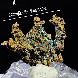 Puede incluir: Esp&eacute;cimen mineral con una superficie texturizada de color marr&oacute;n dorado, acentuada con parches verdes y azules. El esp&eacute;cimen mide aproximadamente 2,4 cm de largo y pesa 5,4 gramos. La letra "A" es visible en la esquina superior izquierda.
