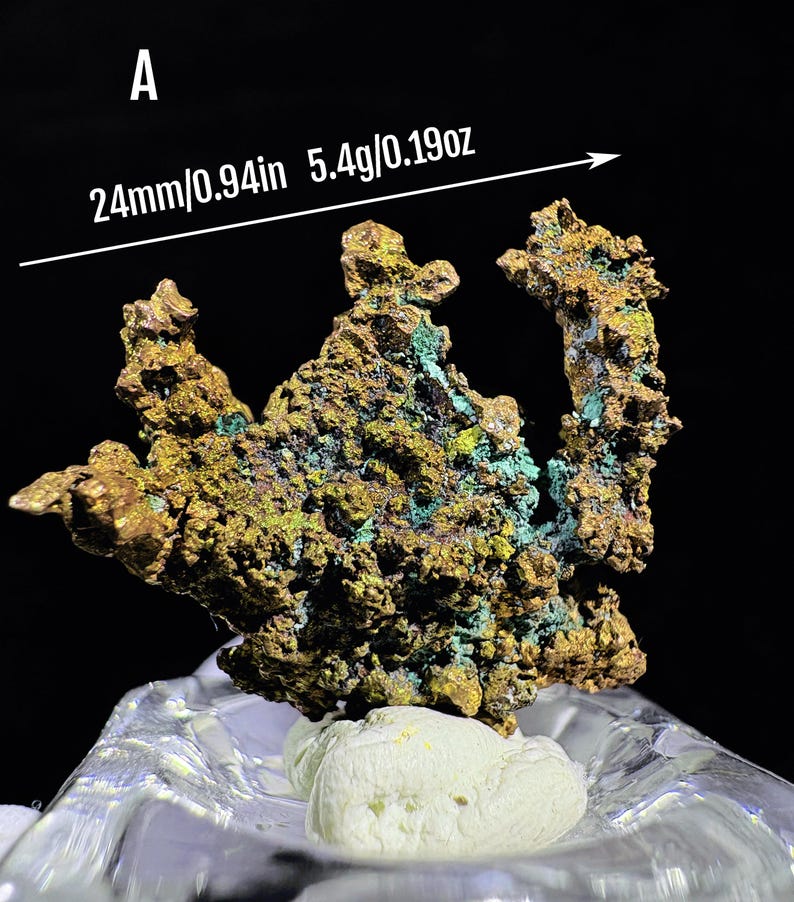 Puede incluir: Esp&eacute;cimen mineral con una superficie texturizada de color marr&oacute;n dorado, acentuada con parches verdes y azules. El esp&eacute;cimen mide aproximadamente 2,4 cm de largo y pesa 5,4 gramos. La letra "A" es visible en la esquina superior izquierda.