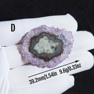 May include: A purple amethyst crystal with a natural druzy formation. The crystal is 1.54 inches in diameter and weighs 9.6 grams. The crystal has a natural, raw look with a variety of purple hues.