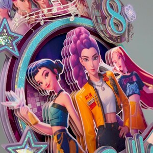 May include: A multi-layered cake topper featuring stylized illustrations of anime-style characters. The design incorporates a teal and purple color scheme, with the number 8 and the word "Bella" visible. The characters are depicted in various outfits and poses.