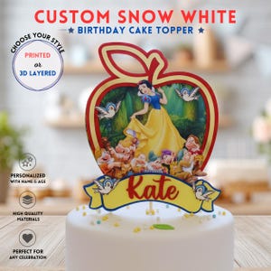 May include: A custom Snow White birthday cake topper shaped like a red apple, featuring Snow White and the seven dwarfs. A yellow banner at the bottom displays the name Kate in red script. The topper includes blue bird illustrations.