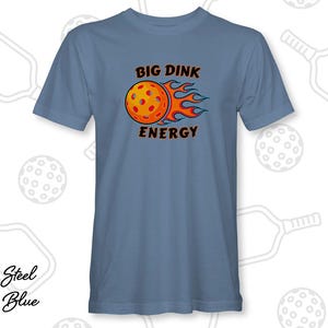 May include: Steel blue t-shirt with the text "BIG DINK ENERGY" above a graphic of a pickleball on fire. The shirt is a solid color and features a crew neck.