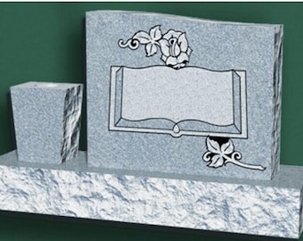 May include: A gray granite headstone with a carved book and rose design. The headstone has a space for an inscription and a separate vase for flowers.