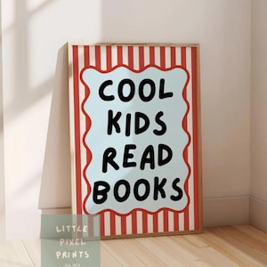 May include: A framed print with the text "COOL KIDS READ BOOKS" in black on a light blue background. The frame has a red and white striped border. The print is leaning against a wall on a wooden floor.