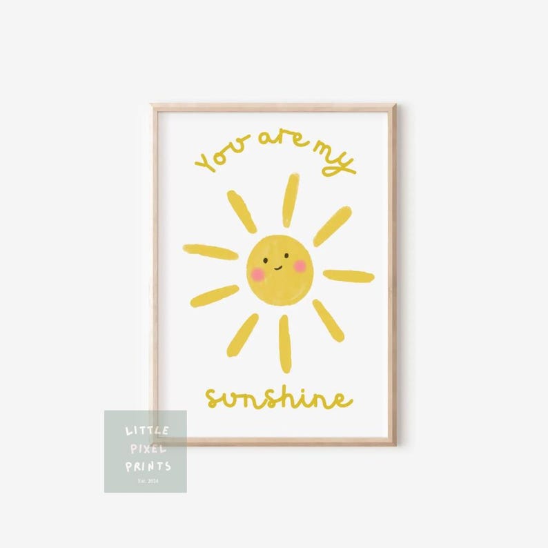 May include: A framed print featuring a yellow cartoon sun with a smiling face and radiating beams. The words "You are my sunshine" are written in yellow script. A small logo is in the lower left corner.