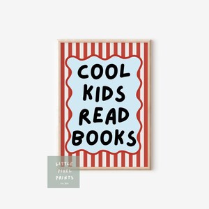 May include: A framed print with the text "COOL KIDS READ BOOKS" in black on a light blue, wavy-edged shape. The background has red and white vertical stripes, and the frame is a light wood color. A small logo is in the lower left corner.