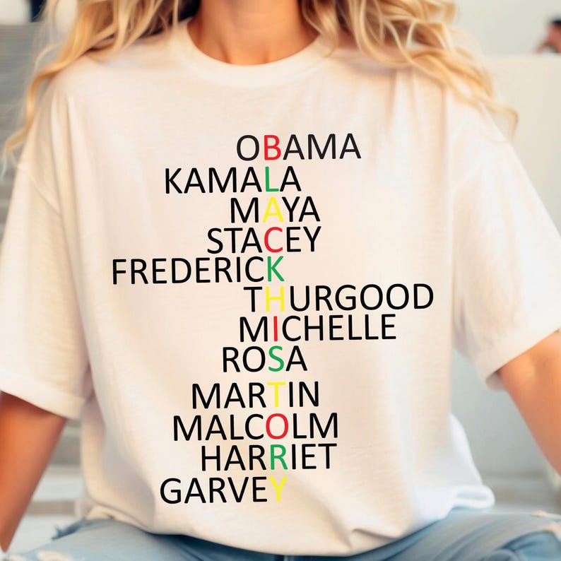 Może przedstawiać: Biała koszulka z czarno-kolorowym wzorem układanki słownej. Słowa to "OBAMA", "KAMALA", "MAYA", "STACEY", "FREDERICK", "THURGOOD", "MICHELLE", "ROSA", "MARTIN", "MALCOLM", "HARRIET" i "GARVEY".