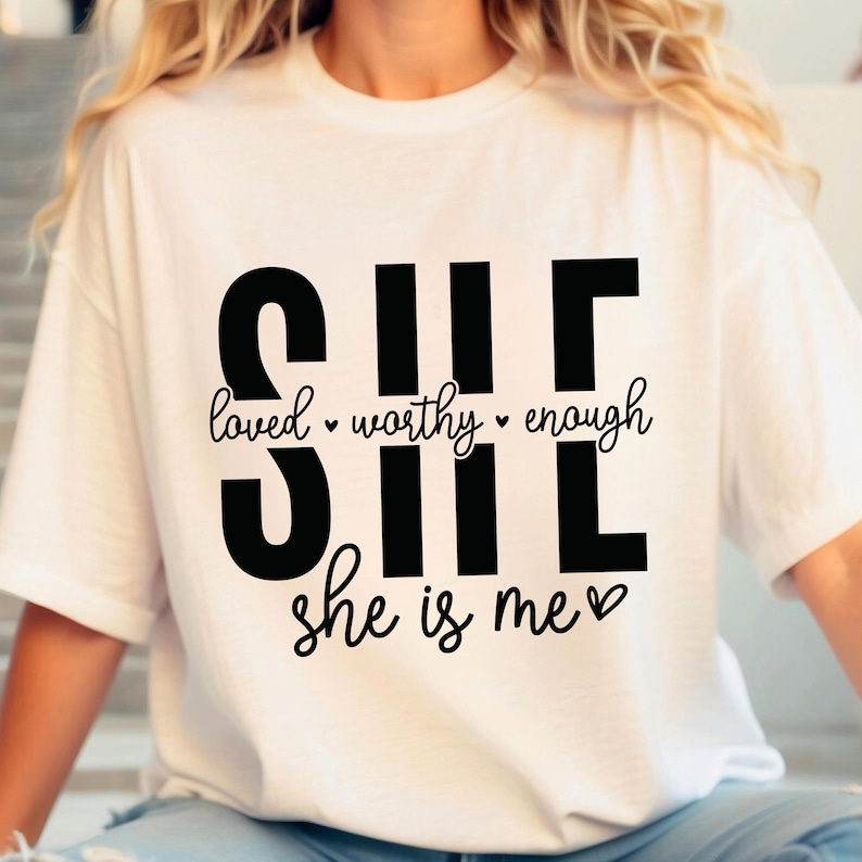 May include: White t-shirt with black text that reads "SHE loved worthy enough she is me" with a heart symbol.