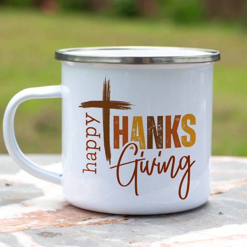 May include: White enamel camping mug with a brown cross and the text "happy THANKS giving" in orange, brown, and yellow.