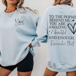 Pu&ograve; includere: Felpa azzurra con la scritta "You Matter" sul davanti e "To the person behind me: You are amazing, beautiful, and enough. Remember that" sul retro. La felpa &egrave; a girocollo.