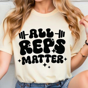 May include: A white t-shirt with a black graphic that says "All Reps Matter" in a retro font with a barbell and stars.