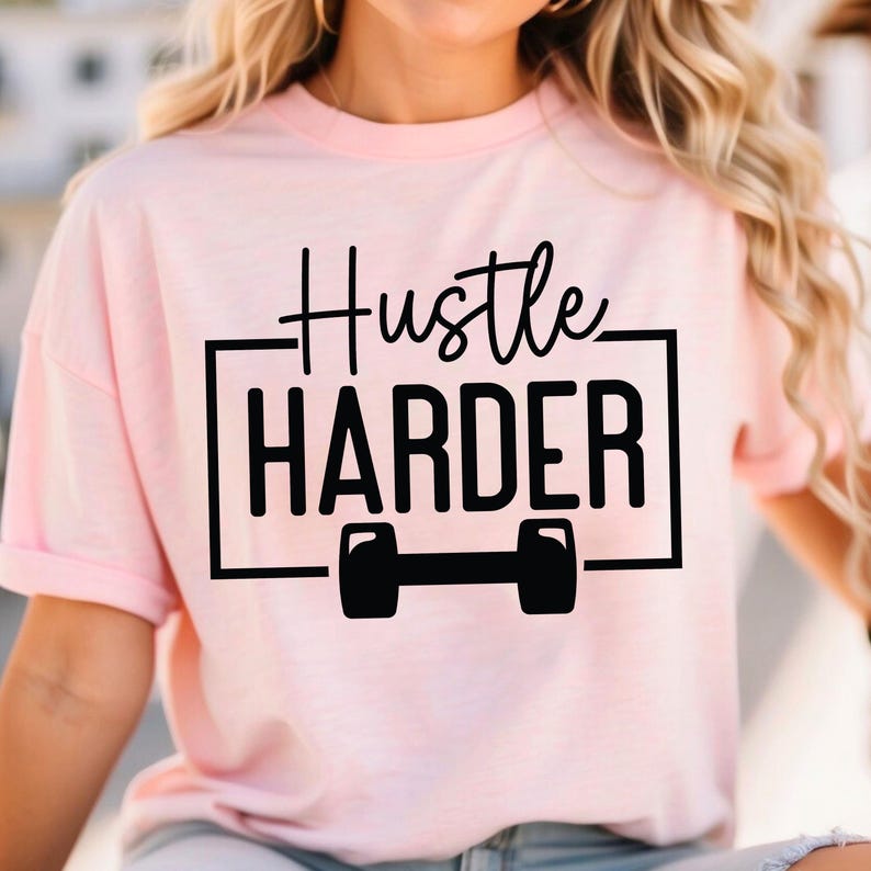 May include: Pink t-shirt with black text that reads "Hustle Harder" and a black dumbbell graphic.