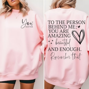Pu&ograve; includere: Felpa rosa chiaro con la scritta "You Matter" sul davanti. La parte posteriore della felpa presenta il testo "To the person behind me: You are amazing, beautiful, and enough. Remember that."