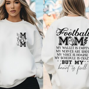 May include: White sweatshirt with black text that reads "Football Mom" and "My wallet is empty, my nerves are shot, my voice is hoarse, my schedule is crazy, but my heart is full".