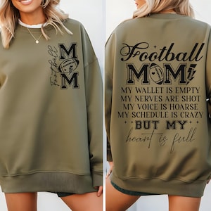 May include: A green sweatshirt with a black graphic that says "Football Mom" and includes a football design. The text below the graphic says "My wallet is empty, my nerves are shot, my voice is hoarse, my schedule is crazy, but my heart is full."