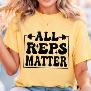 May include: A yellow t-shirt with a black graphic that says "ALL REPS MATTER" in a retro font style. The graphic is surrounded by a black square.