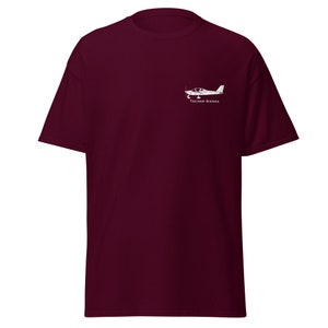 Op de afbeelding: Een maroon t-shirt met een witte afbeelding van een Tecnam Sierra vliegtuig.