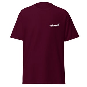 Può includere: T-shirt color borgogna con un contorno bianco di un aereo Cessna 310 e il testo "Cessna 310" stampato sul davanti.