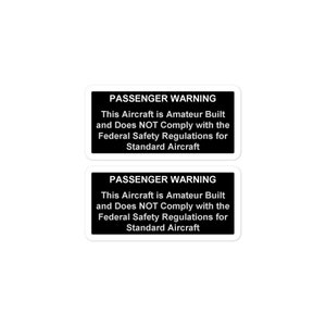 May include: Two black and white warning signs with the text "PASSENGER WARNING" and the message "This Aircraft is Amateur Built and Does NOT Comply with the Federal Safety Regulations for Standard Aircraft."