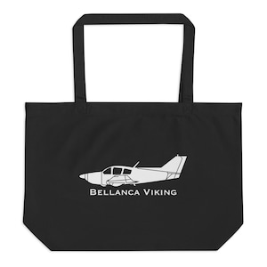 May include: Black tote bag featuring a white outline of a Bellanca Viking airplane. The text "BELLANCA VIKING" is printed below the plane. The bag has two long handles for carrying.