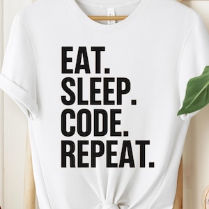 Könnte beinhalten: Weißes T-Shirt mit schwarzem Text, der "Eat. Sleep. Code. Repeat." lautet.