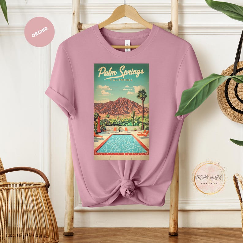 Peut inclure: Un t-shirt rose avec un graphique vintage d'une piscine et de palmiers. Le graphique indique "Palm Springs, Californie".