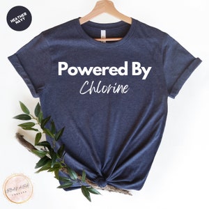 May include: A heather navy blue t-shirt with the text "Powered By Chlorine" in white.
