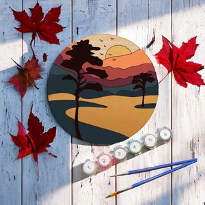 May include: A round wooden painting with a sunset landscape scene. The painting features a brown, yellow, and orange sunset with a blue sky and a silhouette of trees. The painting is surrounded by paint pots numbered 1 through 6.
