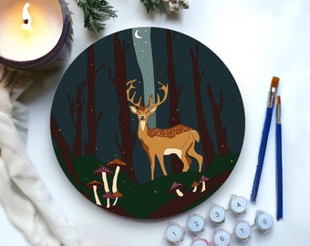 Puede incluir: Un kit de pintura por números con un ciervo de pie en un bosque oscuro con setas y una luna creciente en el cielo. El kit incluye botes de pintura numerados y pinceles.