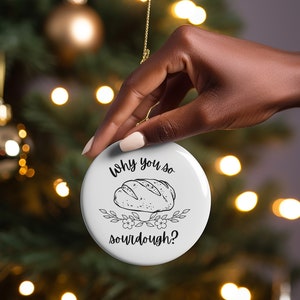 Peut inclure: Ornement de No&euml;l rond blanc avec du texte noir qui dit "Why you so sourdough?" et une illustration en noir et blanc d'une miche de pain au levain.